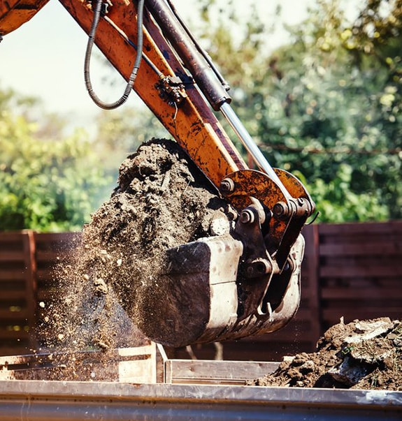 Excavator carrying soil — Demolishing & Remediation In Heatherbrae, NSW