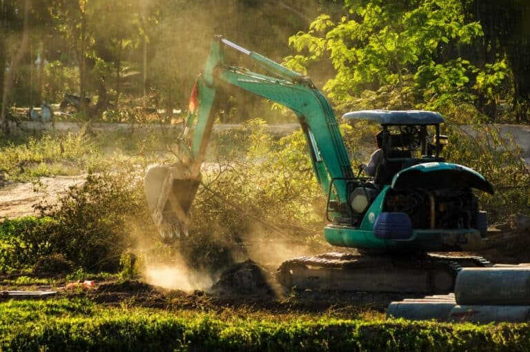 Mini excavator working on dusty soil — Demolishing & Remediation In Heatherbrae, NSW
